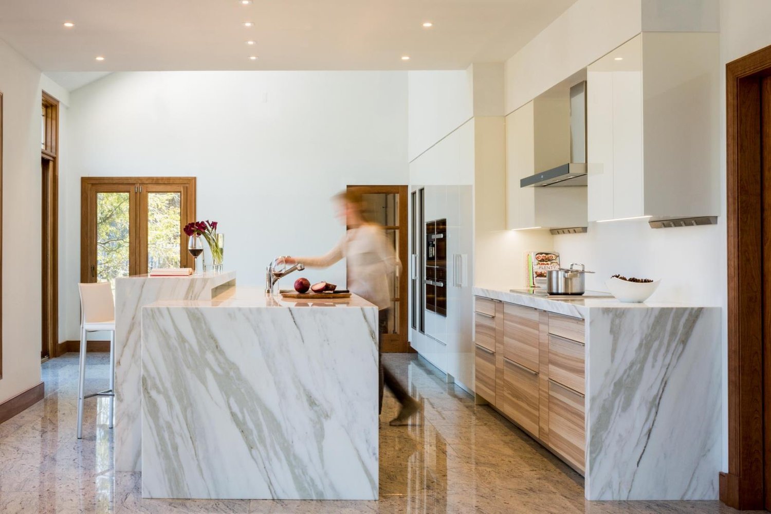 Marble island and warm wood cabinetry in a bright kitchen