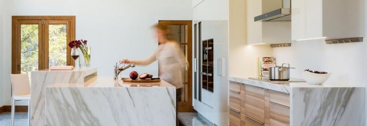 Marble island and warm wood cabinetry in a bright kitchen